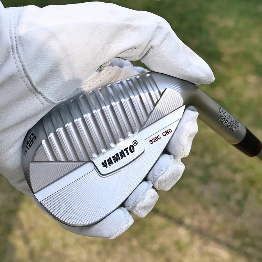 Close-up of golfer holding Yamato wedge head, showcasing craftsmanship