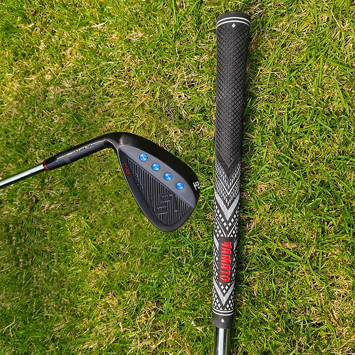 Close-up of Yamato left-handed wedge head resting on grass, with shaft and grip in background
